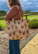 Person carrying a patterned tote bag outdoors with a scenic background
