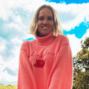 Woman holding a patterned bag outdoors with trees and sky in the background